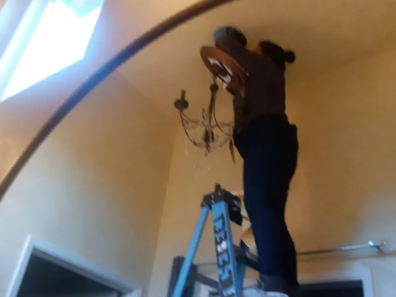Electrician installing a chandelier in a Archbold residence